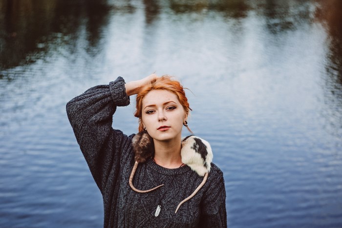 Woman with two rats on her shoulders by a lake