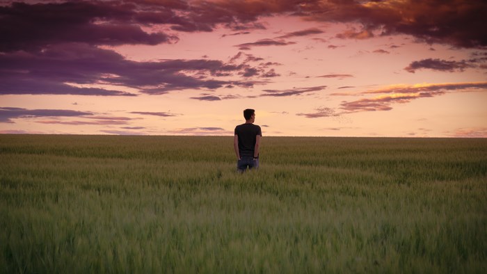 Man standing in a field at sunset