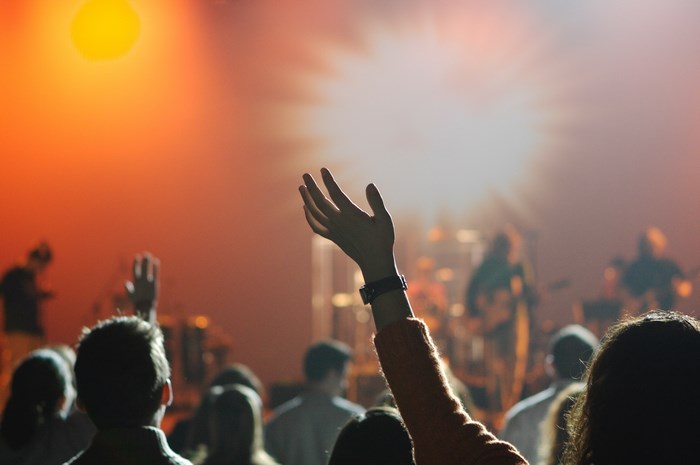 Audience raising hands at a concert with bright stage lights