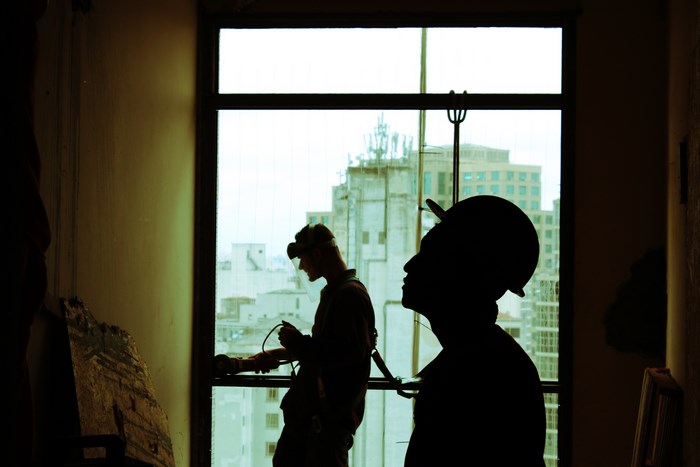 Construction workers with hard hats and tools near a window