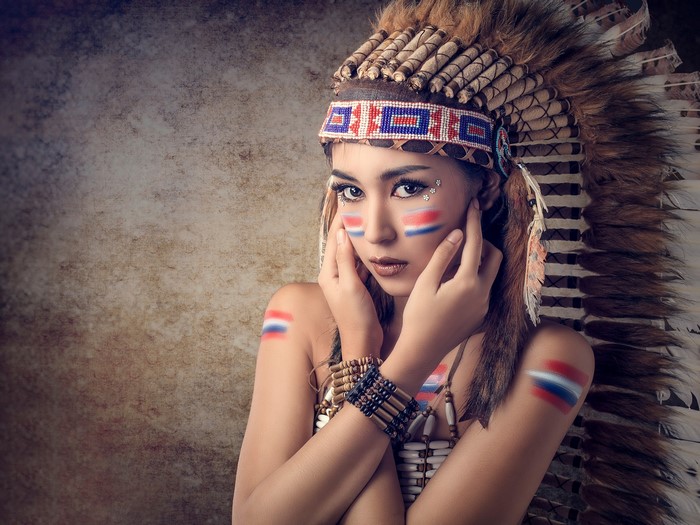 Asian woman in Native American headdress with face paint