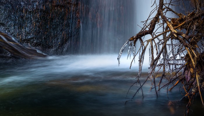 Icy Waterfall with Frozen Branches in Winter