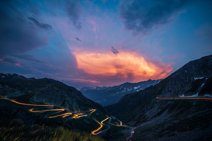Mountain pass road with light trails at sunset in Switzerland
