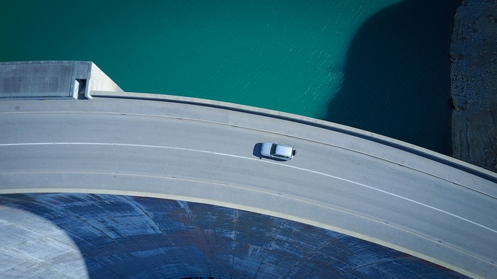 Aerial view of a car on a curved dam road