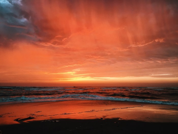 Dramatic sunset over the ocean with red sky and waves