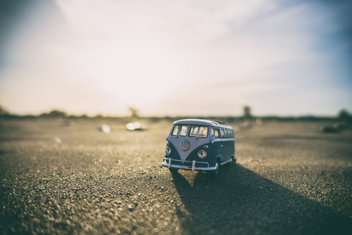 Miniature blue and white Volkswagen bus on sandy ground