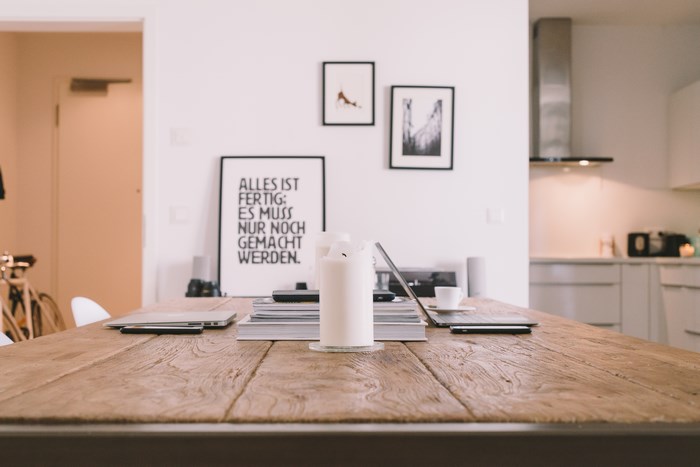 Dining table with laptops, candle, and framed art
