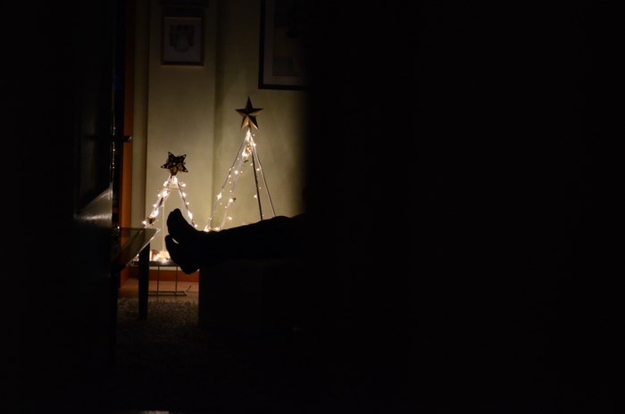 Silhouette of legs resting near Christmas tree lights