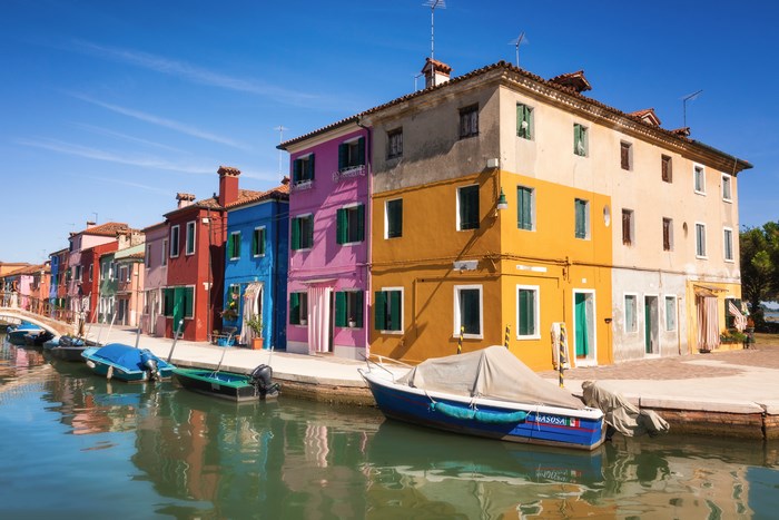 Colorful houses and boats on a canal in Burano, Italy