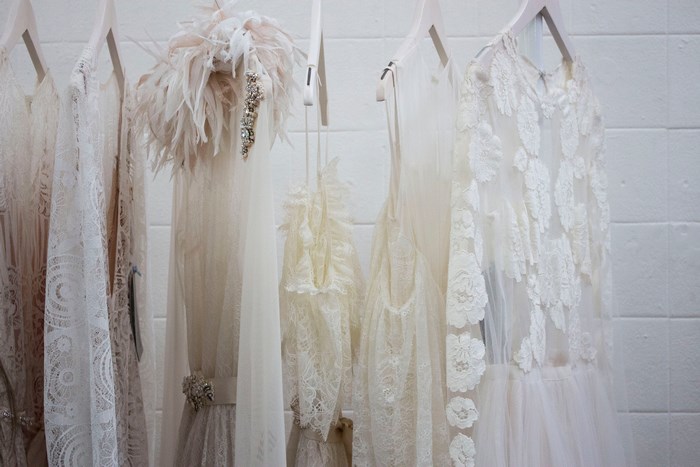 White wedding dresses with lace and feathers on hangers