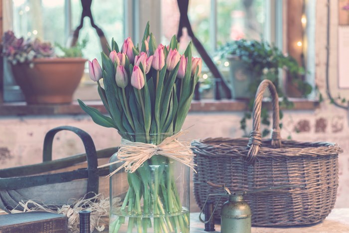 Pink tulips in a glass vase with baskets