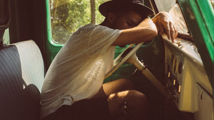 Man in hat sleeping in old green car