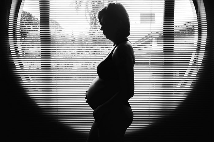 Silhouette of a pregnant woman by a window