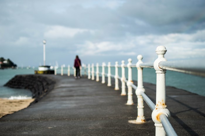 Person walking on a pier with a white railing