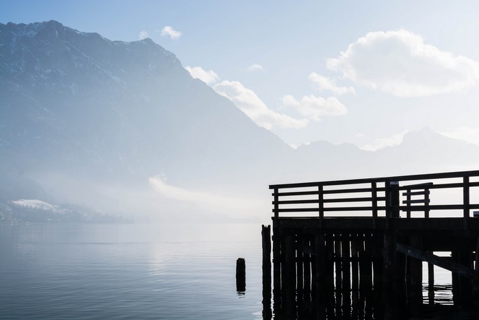 Misty mountain lake with a wooden pier silhouette