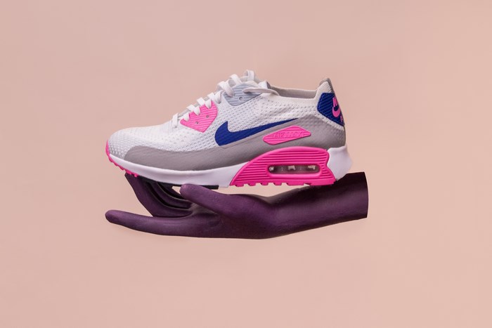 Nike Air Max 90 sneaker held by a purple hand