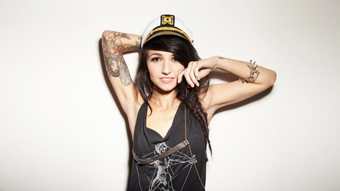 Woman with tattoos wearing a captain's hat
