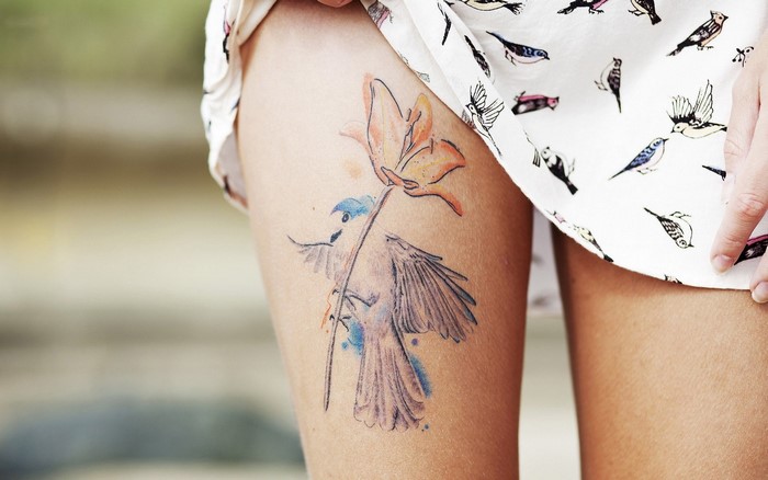 Woman with bird and flower tattoo on leg