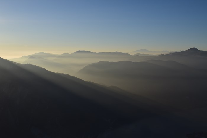 Sunlight rays through fog over mountain ridges at dawn