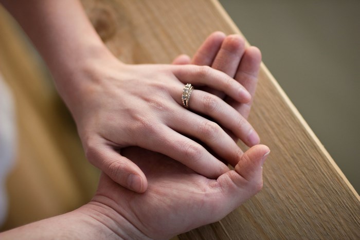 Couple holding hands with engagement ring