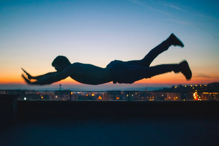 Silhouette of a man levitating over a city at sunset