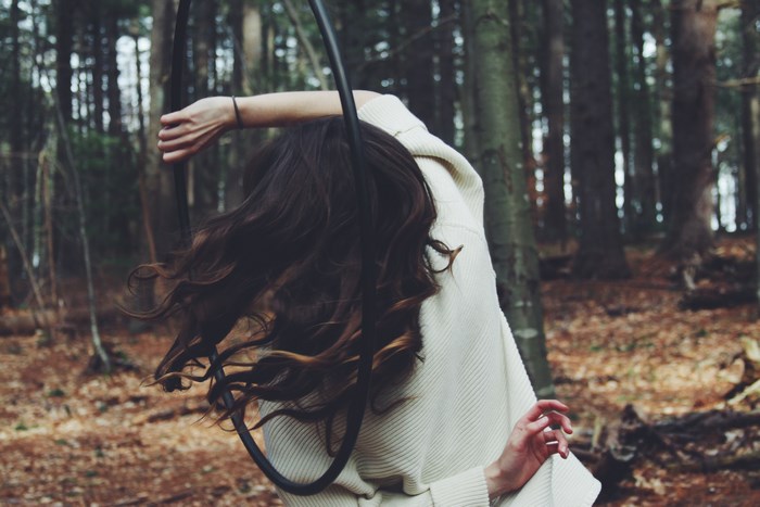 Woman with long hair holding a hoop in a forest