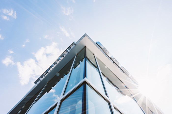 Modern glass building corner against a blue sky
