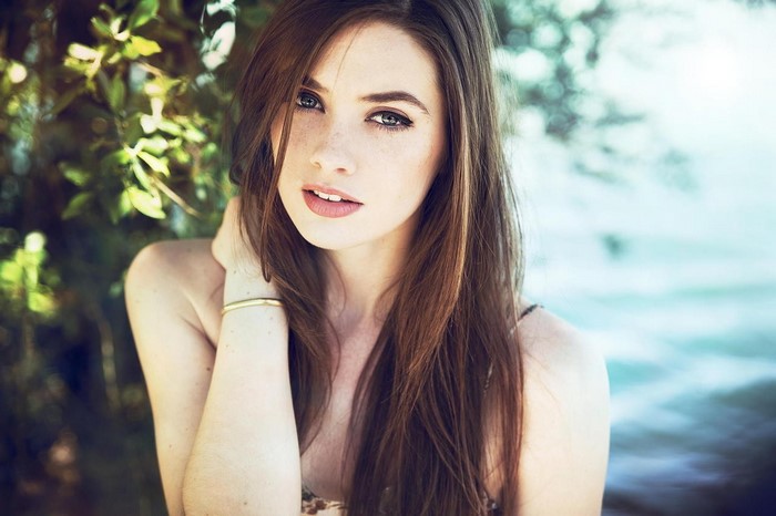 Woman with long brown hair and freckles outdoors