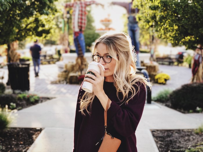 Woman in glasses drinking coffee outdoors