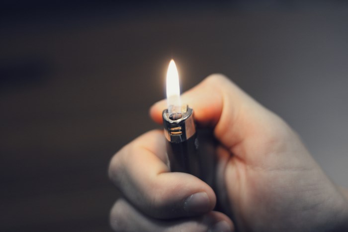 Hand holding a Bic lighter with a flame