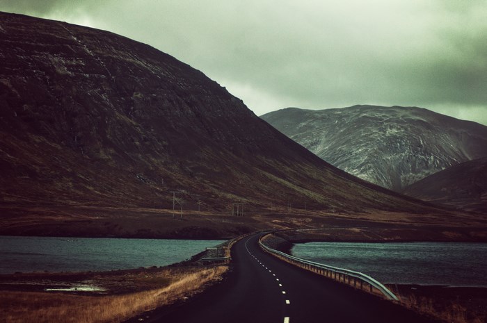Road curving through a mountainous landscape with a lake