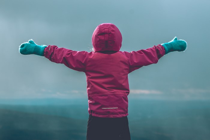 Girl in pink jacket with arms spread wide