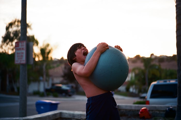 Boy screaming while holding a large ball