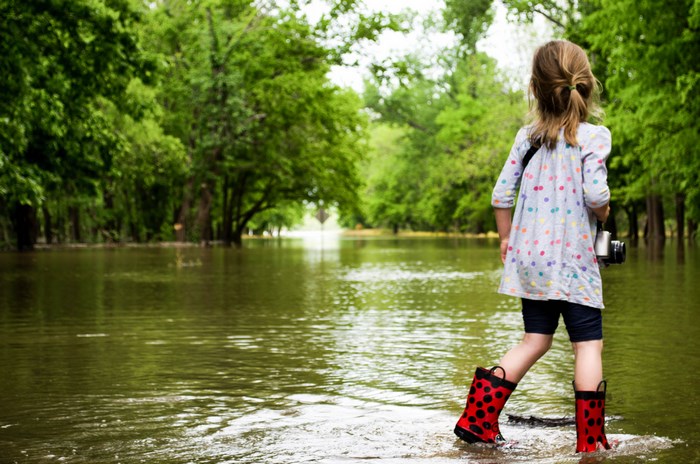Girl in red boots wading through floodwaters
