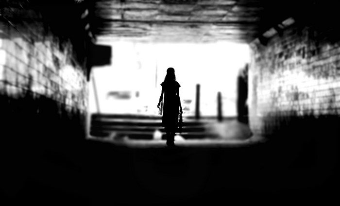 Silhouette of a woman walking through a tunnel