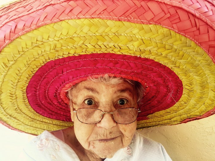 Elderly woman wearing a colorful sombrero and glasses