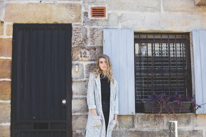 Woman in a coat standing by a stone building