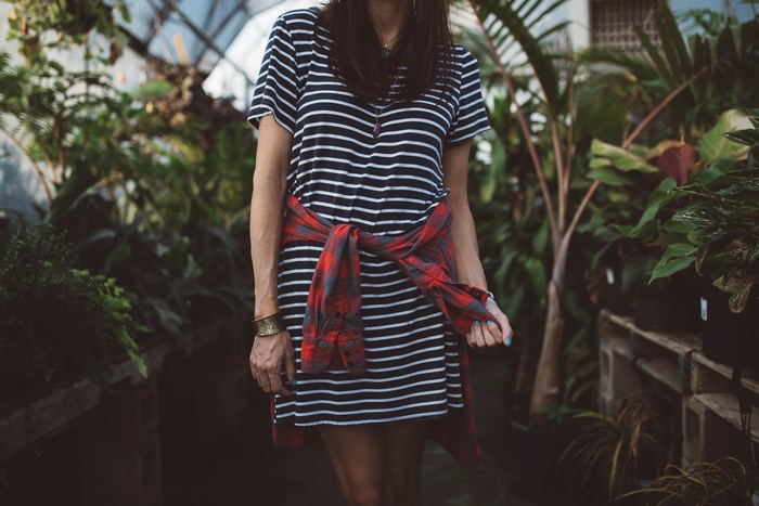 Woman in striped dress with flannel tied around waist in greenhouse