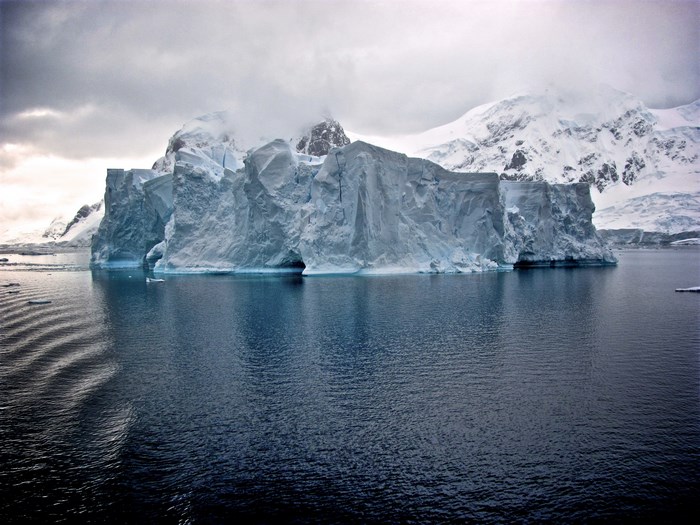 Iceberg in Antarctica with Snowy Mountains