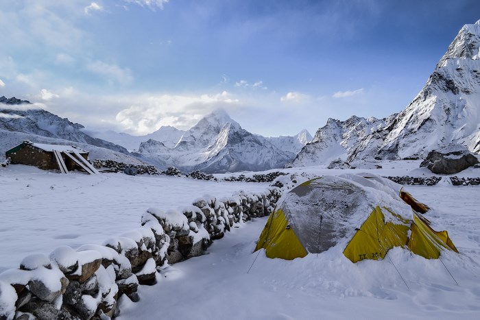 Snowy mountain landscape with tent and cabin