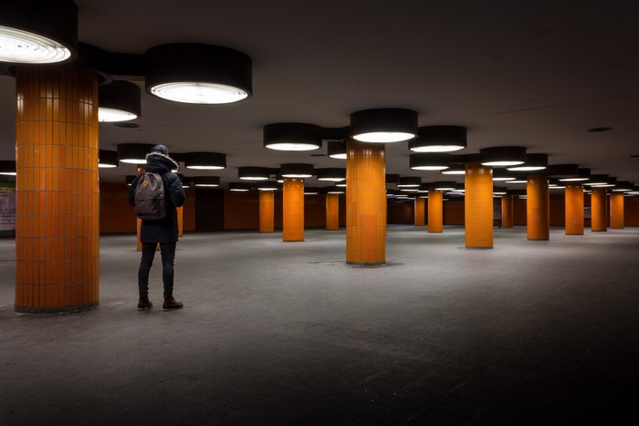 Man with backpack in underground orange pillar station