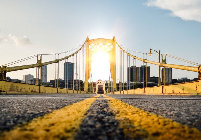 Yellow suspension bridge with city skyline and sun flare