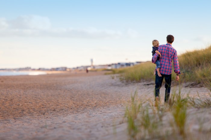 Father and son walking on a sandy beach