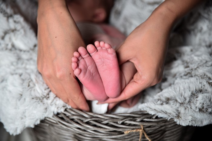 Mother holding newborn baby's feet in a basket