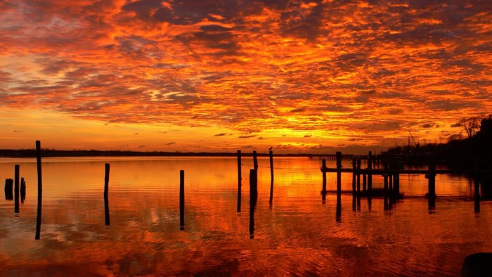Sunset over a calm body of water with wooden posts