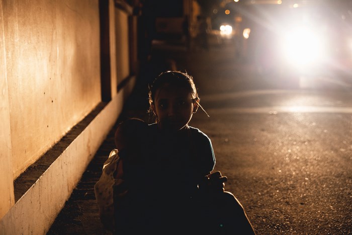 Girl holding a doll on a dark street at night