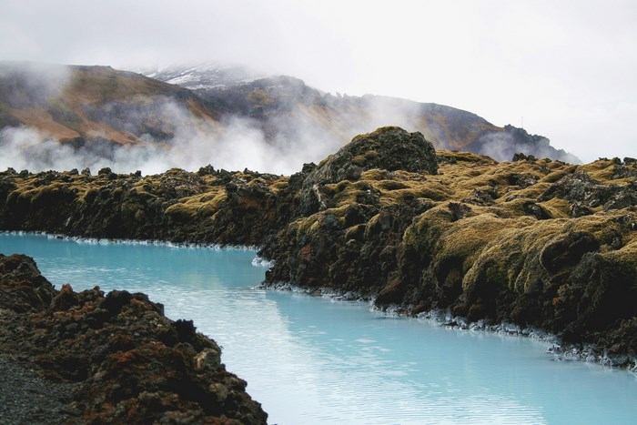 Blue Lagoon with Mossy Rocks and Misty Mountains in Iceland