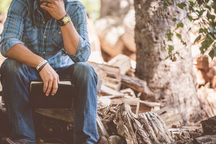 Man in Plaid Shirt Sitting with Bible