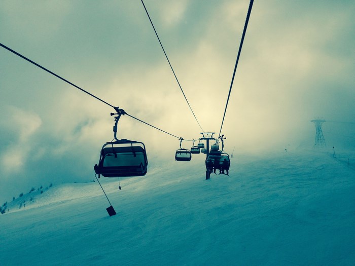 Ski lift ascending a snowy mountain in fog