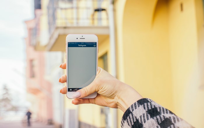 Woman holding an iPhone with Instagram open